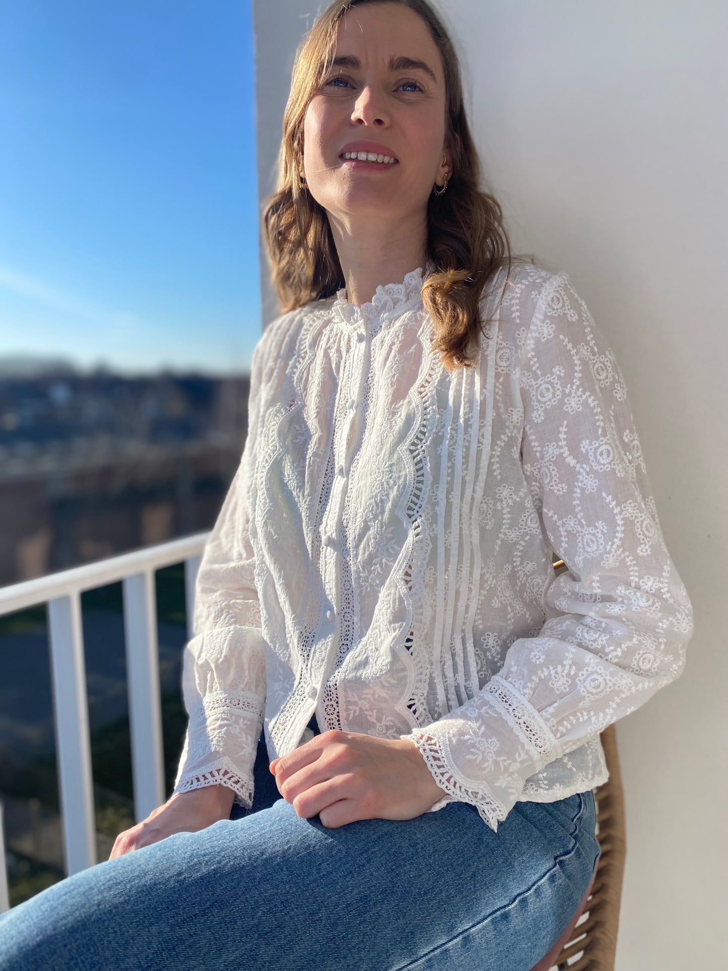 Femme portant la chemise Mélina blanche en dentelle et broderie avec col montant sur un jean.