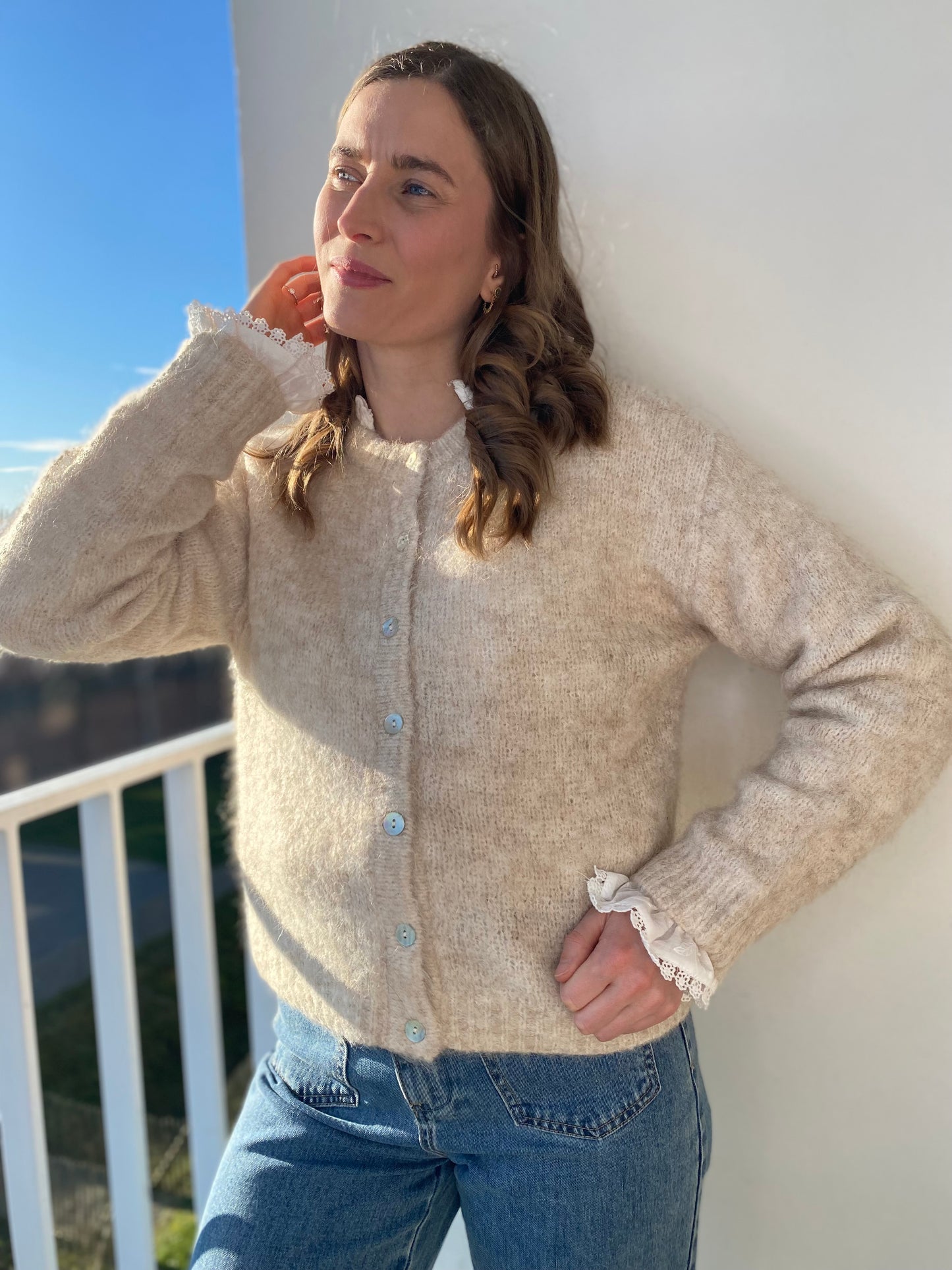 Femme portant le gilet Lala beige chiné sur une chemise à dentelle.